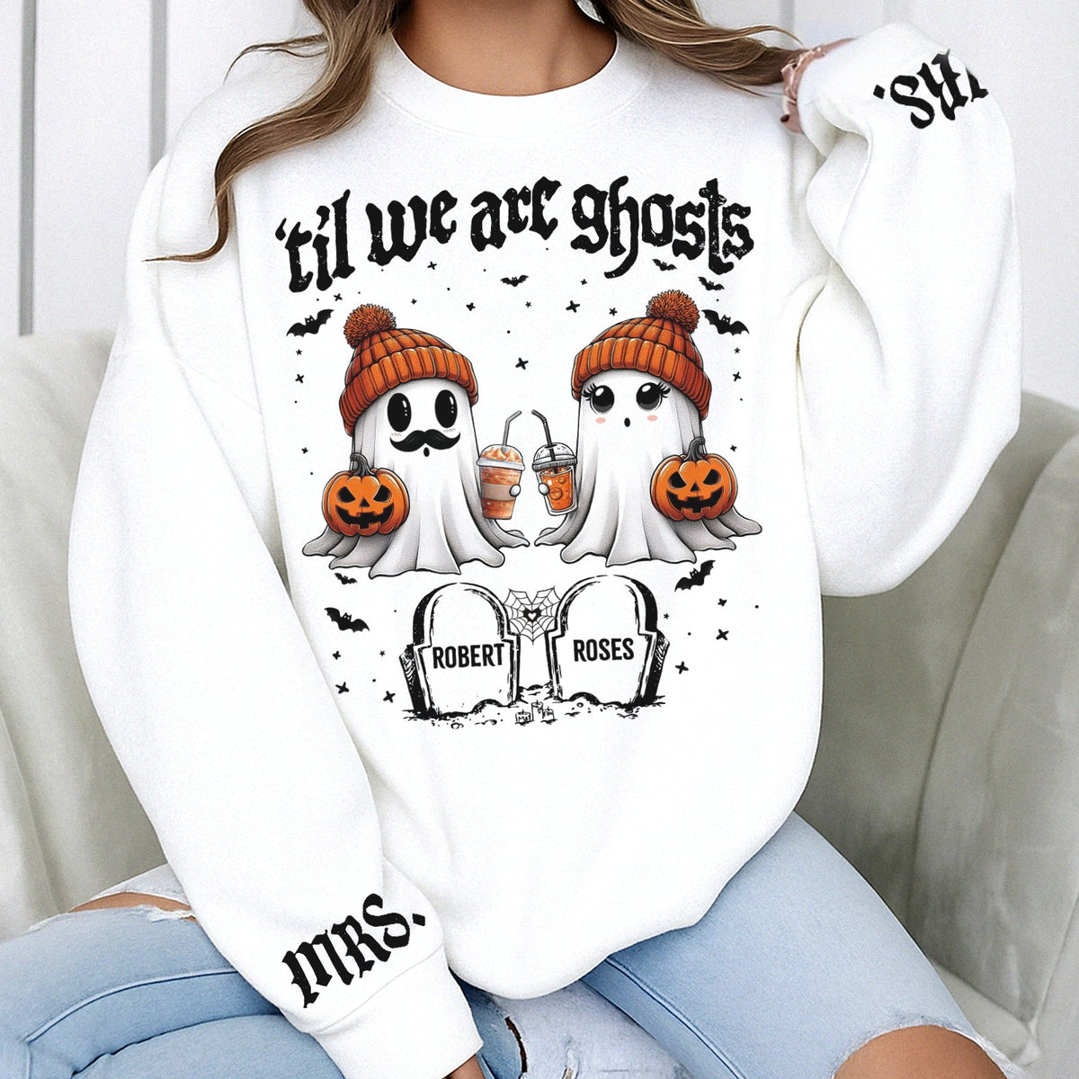 White personalized Halloween couple shirt showing two ghosts in orange beanies holding pumpkins and tombstones with names