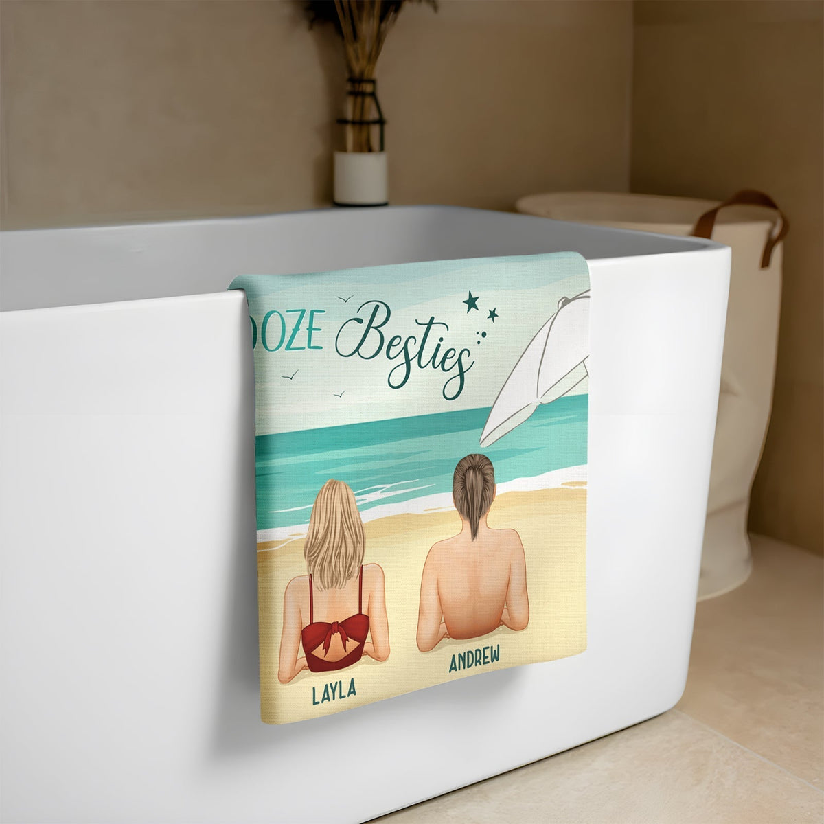 Personalized Beach Towel featuring beach scene draped over bathtub showing two people with names Layla and Andrew