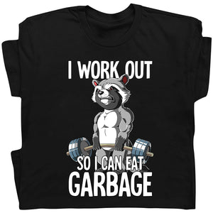 Black t-shirt featuring humorous workout apparel with a muscular raccoon lifting weights and text I work out so I can eat garbage