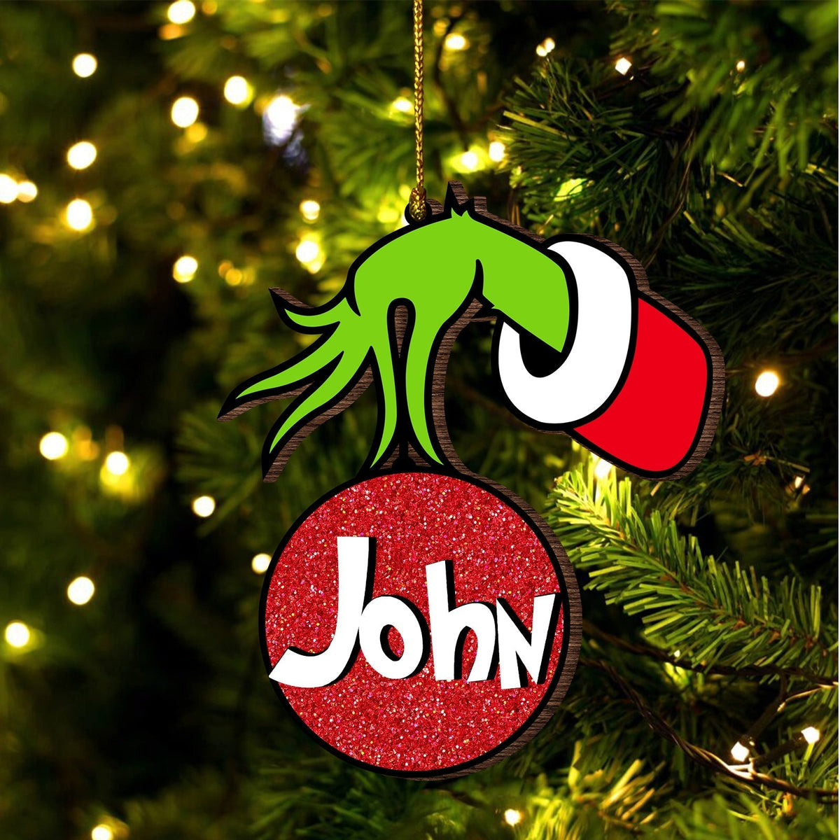 Personalized monster family Christmas ornament with green monster hand and red glitter ball named John hanging on tree